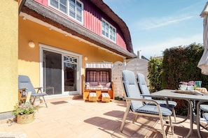 Una casa con un patio, una mesa de comedor y asientos al aire libre.