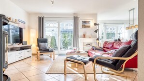 Un salon moderne comprenant un téléviseur, un canapé, un fauteuil et un coin repas.