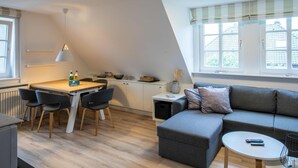 A modern loft bedroom with a large window, a cozy seating area, and a kitchenette. - Vacation apartment Wrixumer Marsch - Located directly on the marsh (Wrixum)