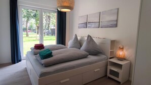 Une chambre à coucher avec un lit, une table de chevet, une lampe et une vue sur l’extérieur.