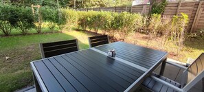 Ein rechteckiger Tisch für draußen mit dunkler Tischplatte und zwei Stühlen.