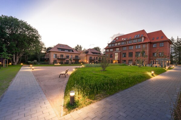 A courtyard with a paved walkway, benches, and a grassy area.