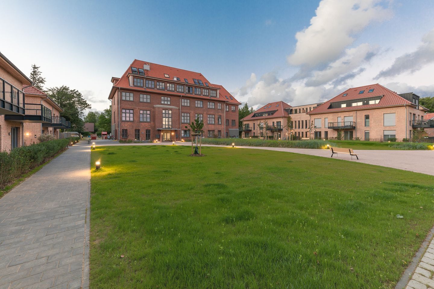 Asuinkerrostalokokonaisuus, jossa on keskeinen nurmialue, päällystettyjä kävelyreittejä ja useita ikkunoita.