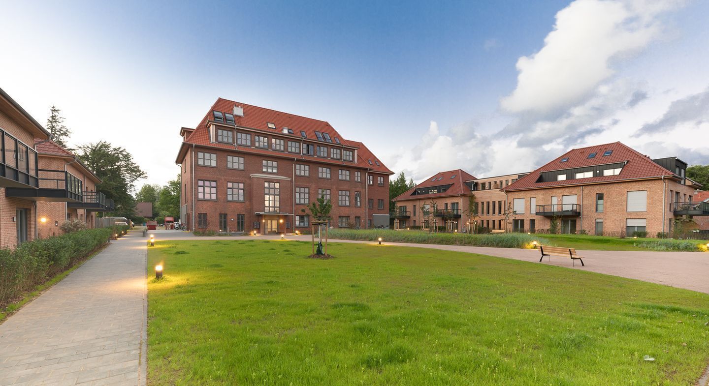 Pátio central com gramado, rodeado por edifícios de tijolo com várias janelas e varandas.