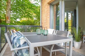 Eine Terrasse mit Tisch und Stühlen, einem Blumentopf und Blick auf ein Backsteinhaus.
