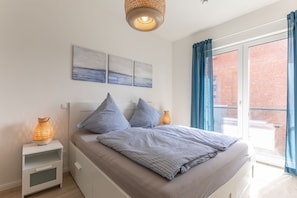Un dormitorio con cama, mesitas de noche y ventana con cortinas.