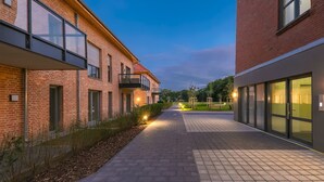 A pathway between buildings with brick facades, a paved walkway, and outdoor exercise equipment.