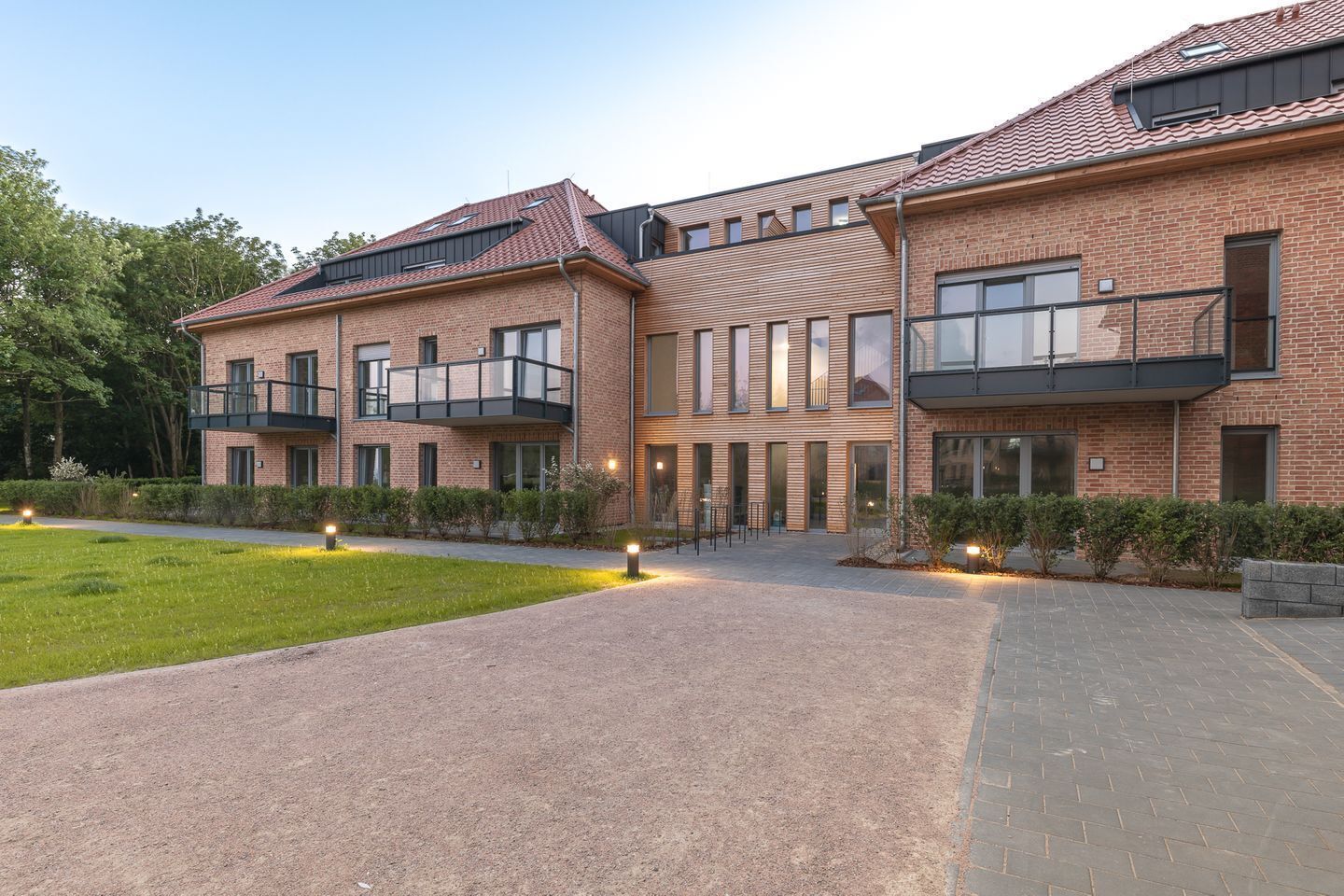 Ein modernes Gebäude mit Backsteinwänden, großen Fenstern und einer gepflasterten Eingangsbereiches.