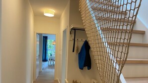 Ein Flur mit Treppe, einer weißen Bank und einer Wand mit Netzvorhängen.