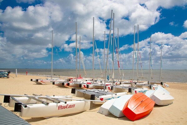 Une plage où sont amarrés plusieurs voiliers, avec une bouée de sauvetage et un ciel dégagé.