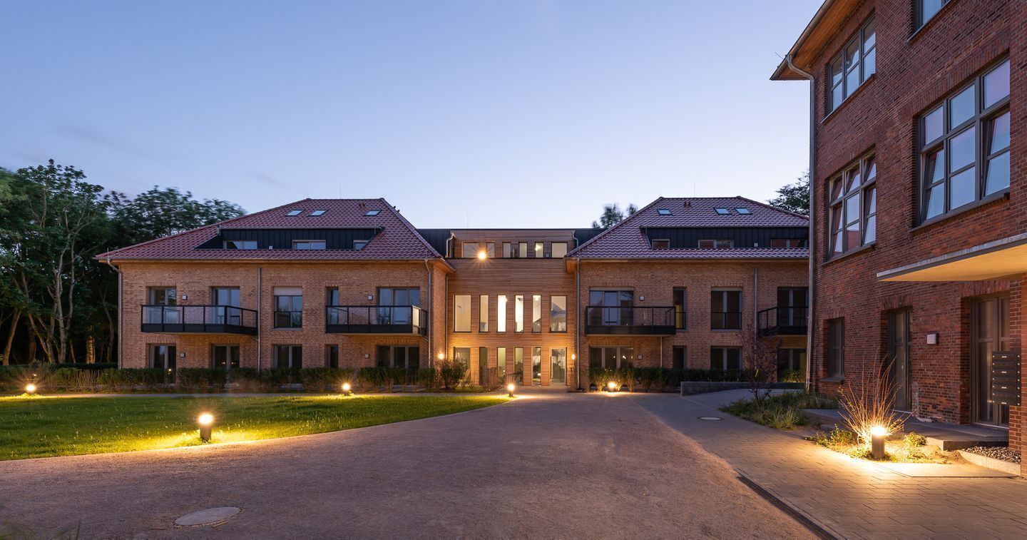 A large brick building with multiple balconies and a central entrance.