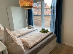 A bedroom with a bed, a wardrobe, and a window with curtains.