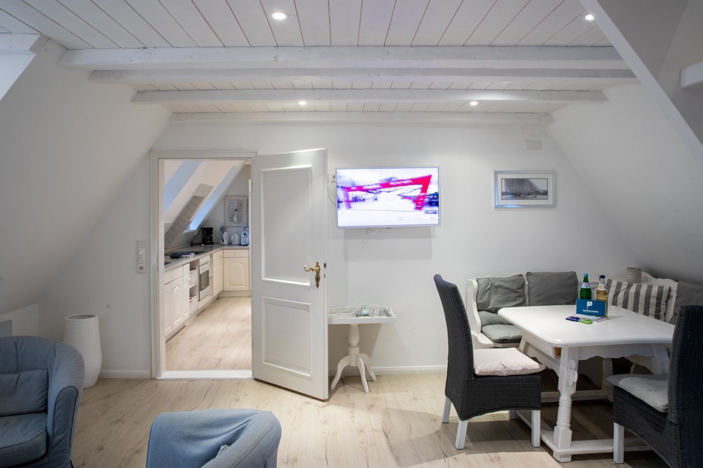 Een modern appartement met een eethoek, keuken en een aan de muur bevestigde televisie.