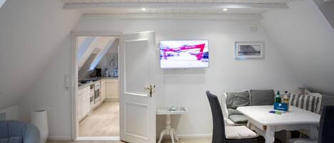Een modern appartement met een eethoek, keuken en een aan de muur bevestigde televisie.