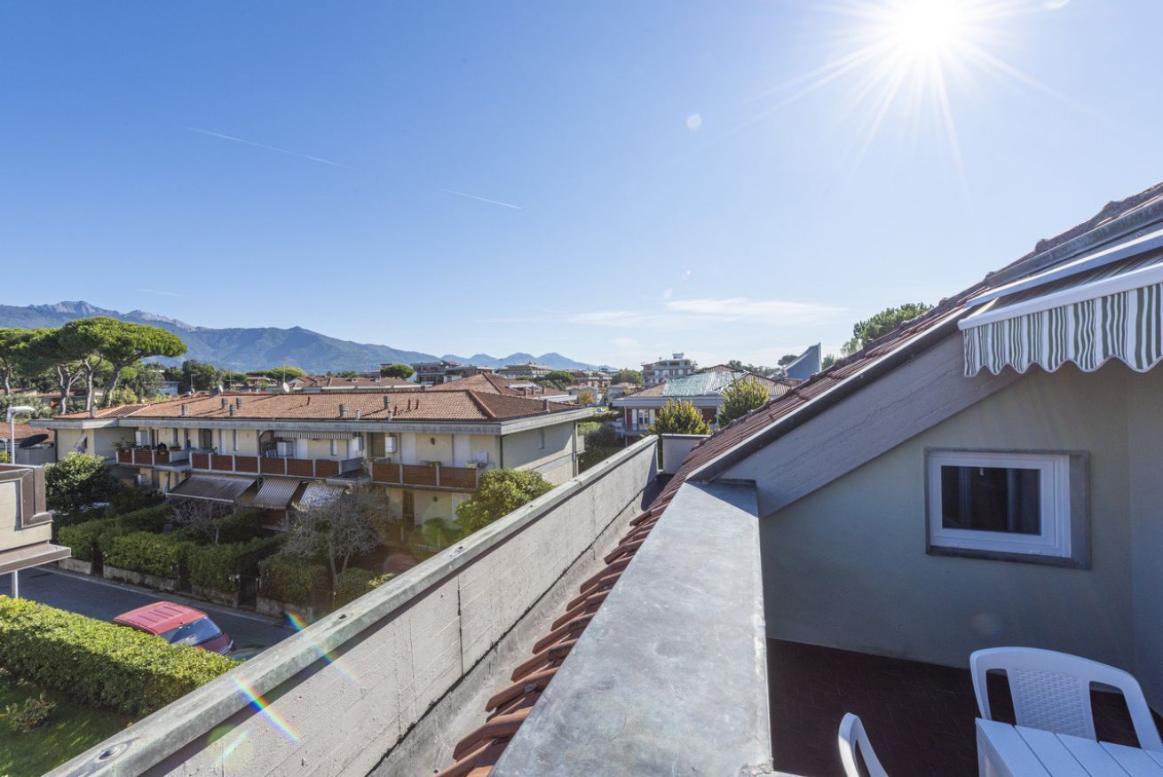 A residential balcony with a view of neighboring houses and mountains.
