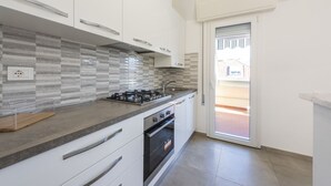 Una cocina moderna con armarios blancos, salpicadero de azulejos, estufa a gas y horno empotrado.
