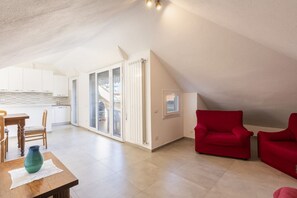 A spacious loft with a dining area, red sofas, and a kitchen with white cabinets.