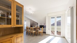 Una habitación amplia con comedor, un mueble de madera y un ventanal corredero que da a un espacio exterior.