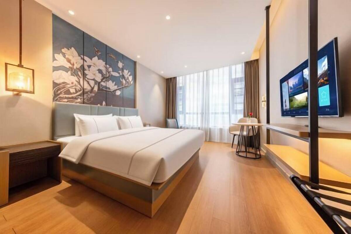 A modern hotel room with a large bed, a desk, and a TV.