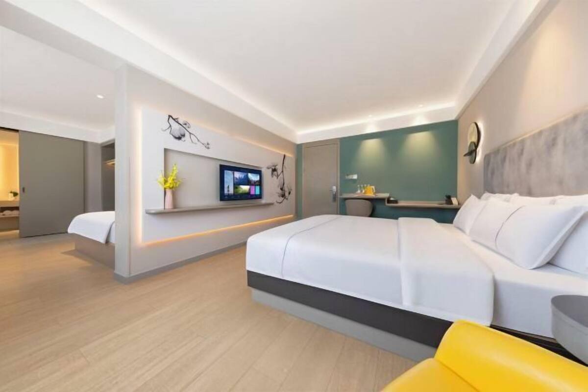 A modern hotel room with a large bed, a TV, a small desk, and a bathroom.