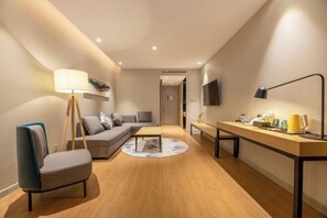 Una sala de estar moderna con un sofá, una silla, una mesita de centro y un escritorio con una lámpara.
