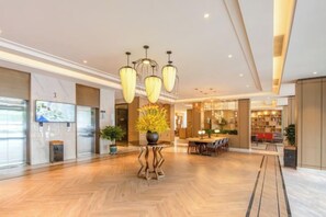 A spacious lobby with a herringbone floor, a central plant arrangement, and a modern chandelier. - Magnotel Hotel (Yan'an Baota Mountain Hundred Meter Avenue) (Yan'an)