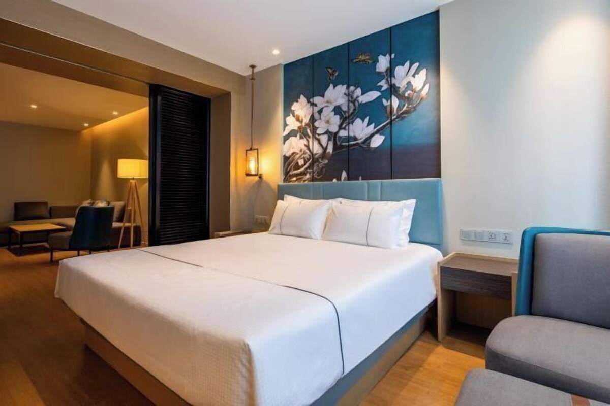 Una habitación de hotel con una cama grande, un escritorio, una silla y una obra de arte colgada en la pared.