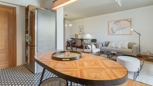 Eine moderne Küche mit einem eingebauten Kühlschrank, einem runden Holztisch und einer Sitzecke mit einer Couch und Sesseln.