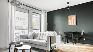 Ein modernes Wohnzimmer mit einem grauen Sofa, einem kleinen runden Tisch und einem Esstisch mit Stühlen.