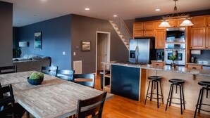 Una cocina moderna con armarios de madera, una isla central con taburetes, una estufa integrada y un refrigerador.