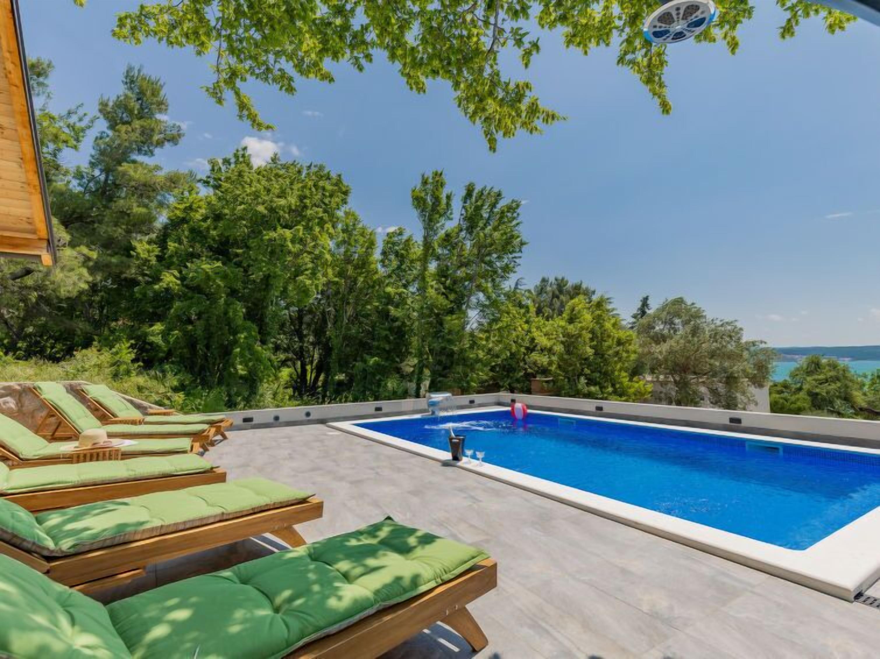 A swimming pool with lounge chairs and a view of the sea.