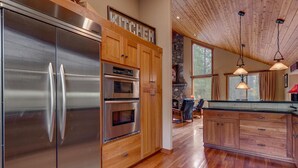 Une cuisine moderne dotée d’appareils électroménagers en acier inoxydable, de meubles de rangement en bois et d’une cheminée en pierre.