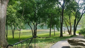 Un parc avec un lac, des arbres et un sentier.