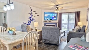 Un salon moderne comprenant un coin repas, un téléviseur à écran plat et un ventilateur de plafond.