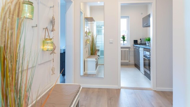 A modern kitchen with stainless steel appliances, a white countertop, and a view into the dining area.