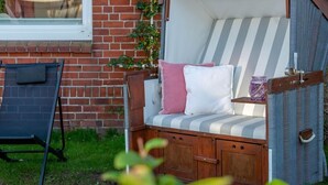 A garden seating area with a striped cushioned bench, a small table, and a chair.