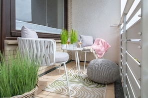 A small outdoor seating area with a table, two chairs, a potted plant, and a decorative rug. - Königsmann - Close to the beach and centrally located, modern vacation apartment with (Sylt)