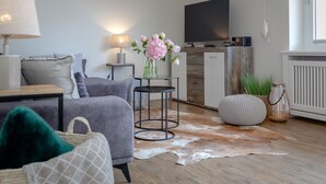 Een moderne woonkamer met een bank, een salontafel, een lamp, een televisie en een kleden van koeienhuid.