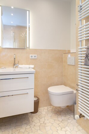 Une salle de bain avec un lavabo blanc, un miroir et des toilettes.