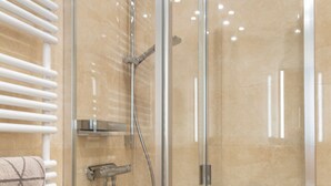A glass-enclosed shower with a white tiled floor and a glass door. - Königsmann - Close to the beach and centrally located, modern vacation apartment with (Sylt)