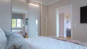 A bedroom with a large bed, a mirror, and a view into another room.