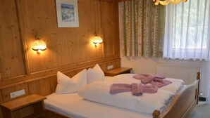 Une chambre aux murs lambrissés, avec un lit, deux tables de chevet et des lampes fixées au mur.