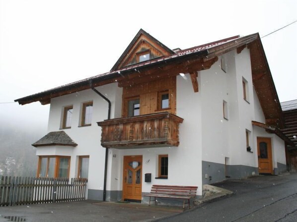 A two-story building with a wooden balcony, a wooden door, and a small porch area. - Silvretta by Interhome (Kappl)