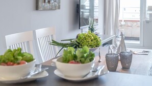 Ett modernt matområde med ett träbord, vita stolar, en krukväxt och en hänglampa.
