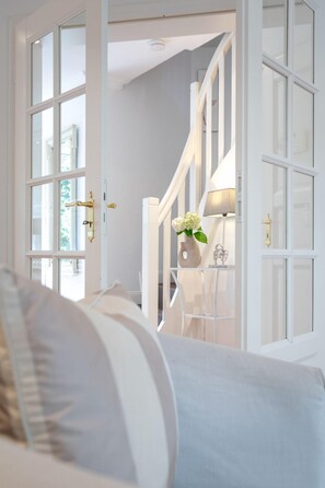 Une pièce avec un lit, une porte blanche et un escalier menant à un autre niveau.