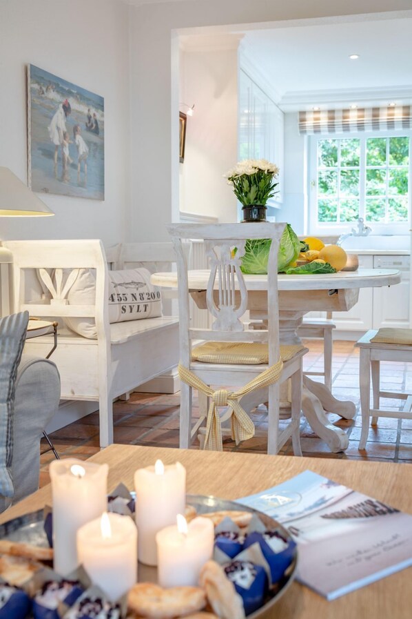 Un coin repas avec des meubles blancs, une table décorée de bougies et un tableau accroché au mur.