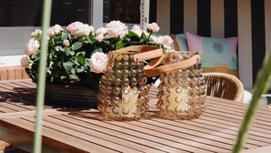 Et træbord med to dekorative glasvaser og en potteplante med lyserøde blomster.