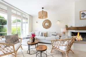 A cozy living room with a white sofa, wicker chairs, a coffee table, and a fireplace. - Tortuga - Spacious vacation home in the dreamlike captain's village of Keitum (Sylt-Ost)