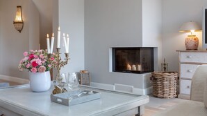 A modern living room with a fireplace, a white coffee table, and a cozy seating area.