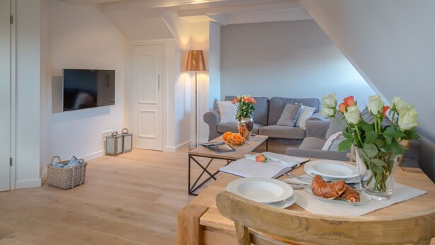 Ein modernes Wohnzimmer mit einer Couch, einem Couchtisch mit Speisen und einem an der Wand befestigten Fernseher.